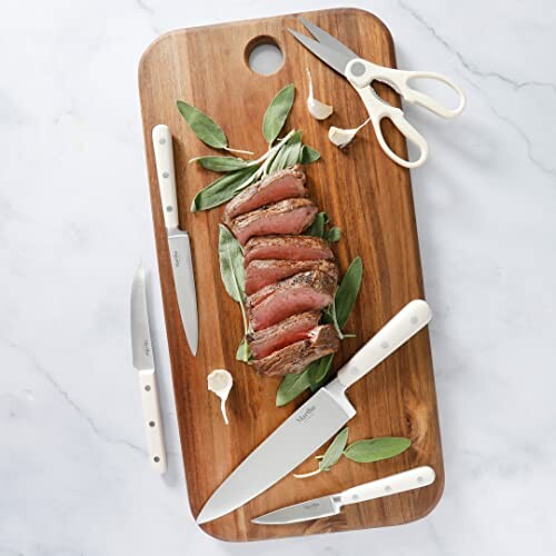 Wooden cutting board with knives, scissors, and sliced steak