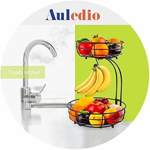 Two-tier fruit basket with assorted fruits next to a kitchen faucet.