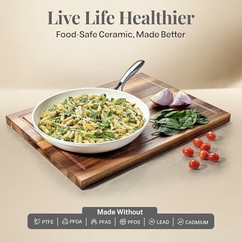 Ceramic pan with pasta, spinach, tomatoes on wooden board.