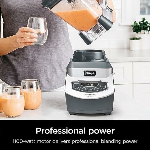 Person pouring smoothie from Ninja blender into a glass on a kitchen counter.