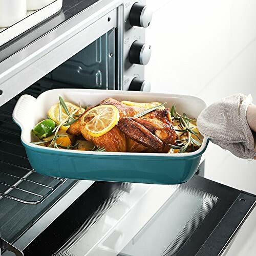 Roast chicken with lemon and herbs in a baking dish being placed in an oven.