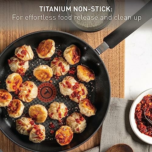 Non-stick pan with dumplings and chili sauce.